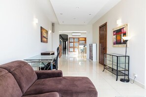 A modern living room with a sofa, a glass coffee table, and a dining area with a table and chairs. - Stylish penthouse in central Sliema on The Strand, Triq Ix-Xatt. Featuring 3 bedrooms, 2 bathrooms, a bright living area, and a large terrace with stunning views of Manuel Island and Valletta. Ideal for families, groups, or business stays. (Sliema)