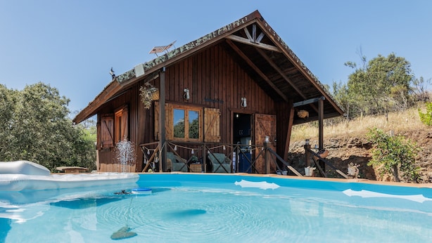 Un edificio rústico de madera con una piscina delantera.
