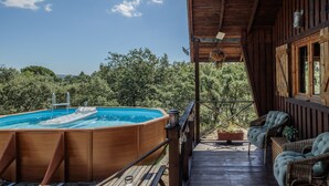 Una terraza exterior con un jacuzzi, mobiliario de mimbre y piso de madera.