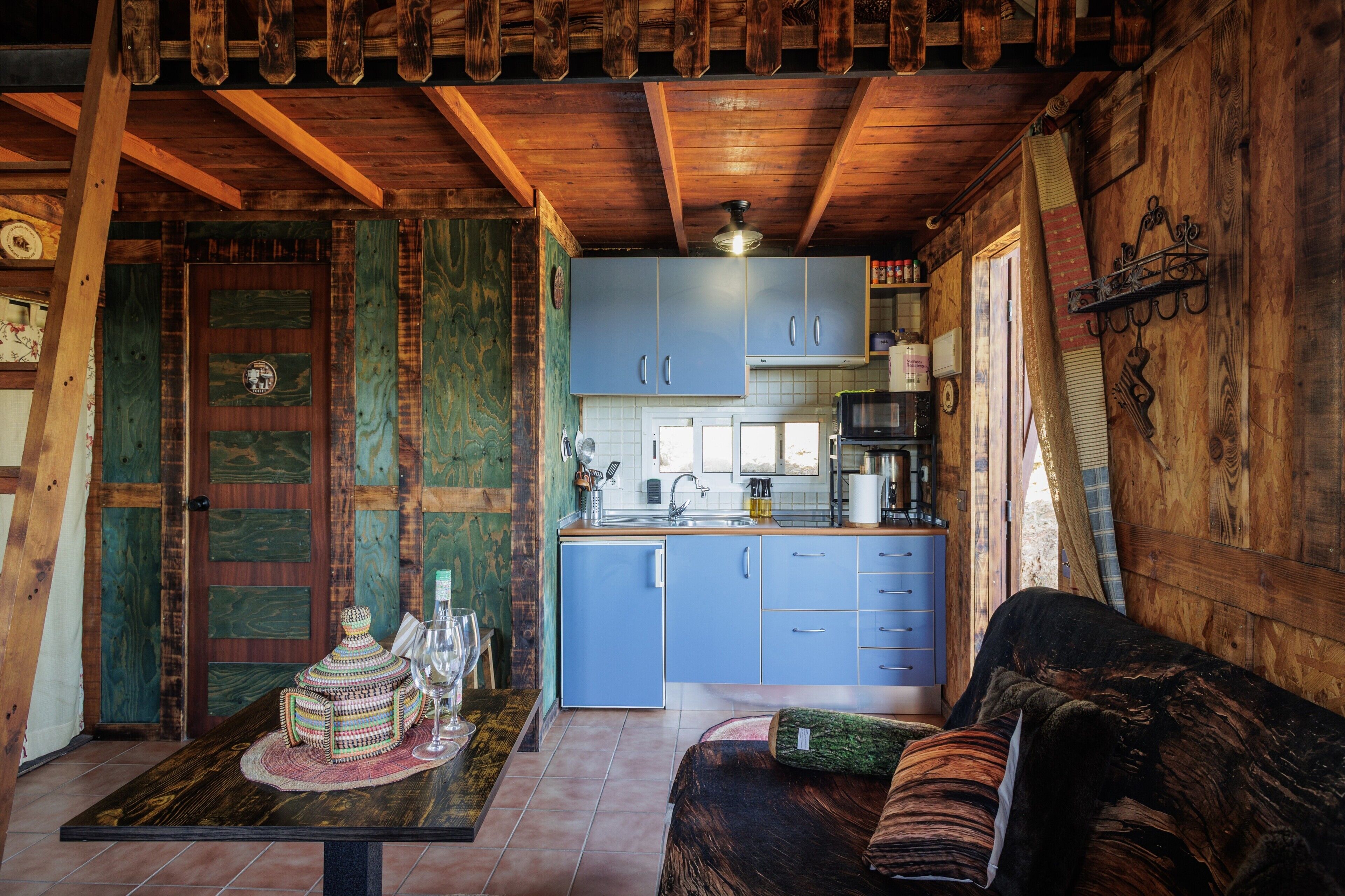 A rustic cabin interior with a dining area, kitchen, and a cozy seating area.