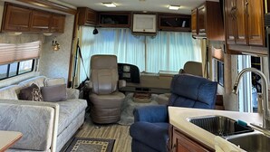 Interior de una caravana con kitchenette, zona de estar e iluminación empotrada en el techo.
