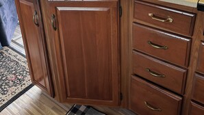 Una cocina con gabinetes de madera, un lavamanos y una ventana con persianas.