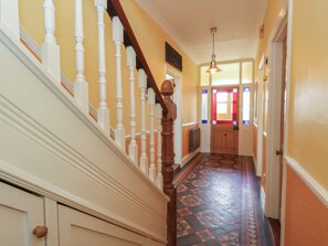 A hallway with a patterned floor, a wooden staircase with white balusters, and a door with stained glass windows. - Millmead House (Weymouth)