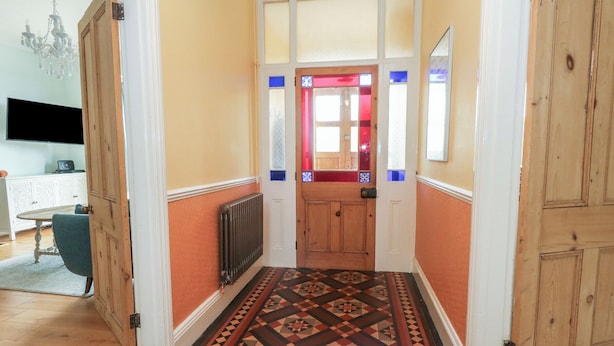 A hallway with patterned flooring, wooden doors, and a radiator. - Millmead House (Weymouth)