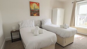 A hotel room with two beds, a nightstand, a wardrobe, and a painting on the wall. - Millmead House (Weymouth)