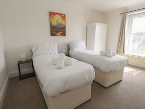 A hotel room with two beds, a nightstand, a wardrobe, and a painting on the wall. - Millmead House (Weymouth)