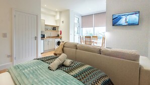 Ett modernt rum med en säng, en soffa, en tv, en tvättmaskin och en matplats.