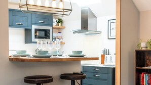 Eine moderne Küche mit Bar, einem Esstisch mit Hockern und einem Wohnbereich mit Sofa und Couchtisch.