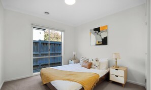 A bedroom with a bed, bedside tables, a window, and a painting on the wall. - Contemporary 4BR2BA house in Point Cook with Study (Point cook)