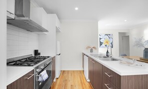 A modern kitchen with a gas stove, oven, and stainless steel sink. - Contemporary 4BR2BA house in Point Cook with Study (Point cook)