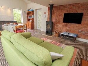 A living room with a sofa, a fireplace, a television, and a dining area with a table and chairs. - Millmead House Annex (Weymouth)