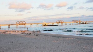 Un muelle se adentra en aguas tranquilas, con una persona de pie al final.