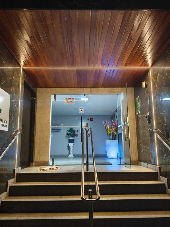 A hotel entrance with a wooden ceiling, marble walls, a sign for the 2nd floor, and a staircase with a handrail.