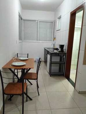 A compact kitchen with a dining table, chairs, and a small countertop with a sink and appliances.
