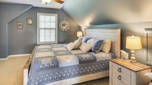 A bedroom with a sloped ceiling, a bed with a quilt, a nightstand with a lamp, and a ceiling fan. - Getaway 1 Mi to Sligo Marina & Center Hill Lake! (Smithville)
