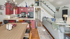 A spacious living area with a dining table, a sofa, and a kitchen with red cabinets. - Getaway 1 Mi to Sligo Marina & Center Hill Lake! (Smithville)