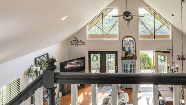 A spacious loft-style living area with a high ceiling, large windows, a staircase, and a view of the outdoors. - Getaway 1 Mi to Sligo Marina & Center Hill Lake! (Smithville)