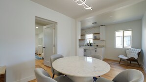 A modern dining area with a marble table and grey chairs, a kitchen in the background, and a large window providing natural light. - 3 Mi to Dtwn! Family & Pet-friendly Gem in Phoenix (Phoenix)
