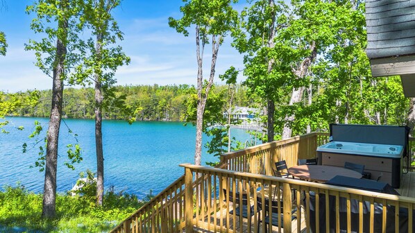 A deck with outdoor furniture overlooking a lake, surrounded by trees.