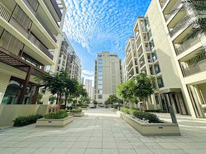 Un quartier résidentiel urbain moderne, composé d’immeubles à plusieurs étages, d’une place centrale ouverte et d’espaces verts.