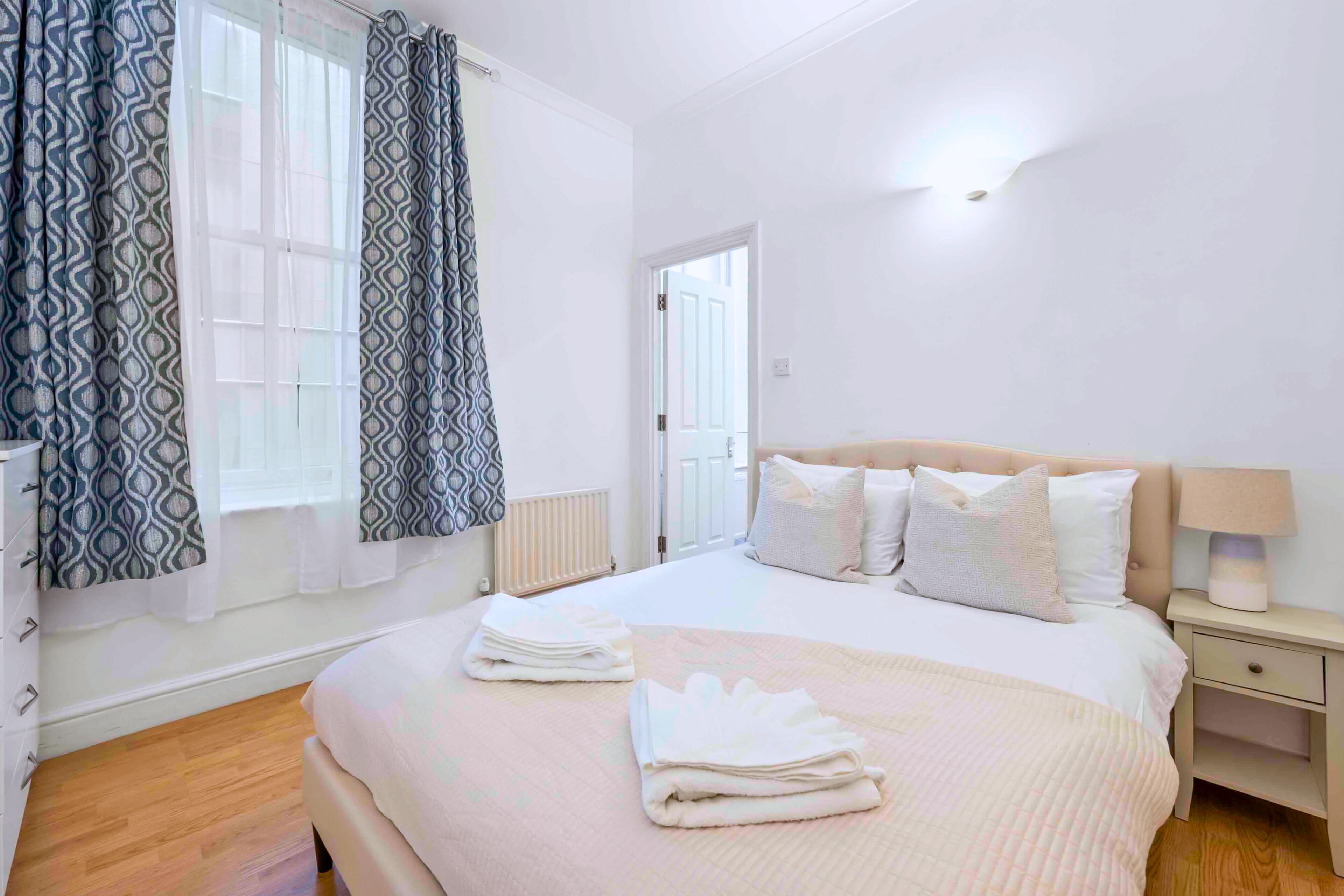 A bedroom with a bed, bedside table, and curtains.