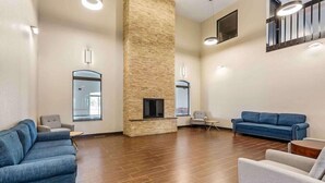 A spacious lobby with a stone column, two sofas, a small table, and a fireplace.
