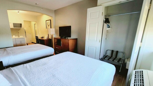 A hotel room with two beds, a television, a desk, and a wardrobe.