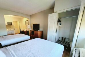 Une chambre d’hôtel avec deux lits, une télévision, un bureau et une armoire.