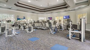 A gym with various exercise equipment, large windows, and a flat-screen TV. - Pool, Parks & Fun! Family Resort Stay Near Disney (Kissimmee)