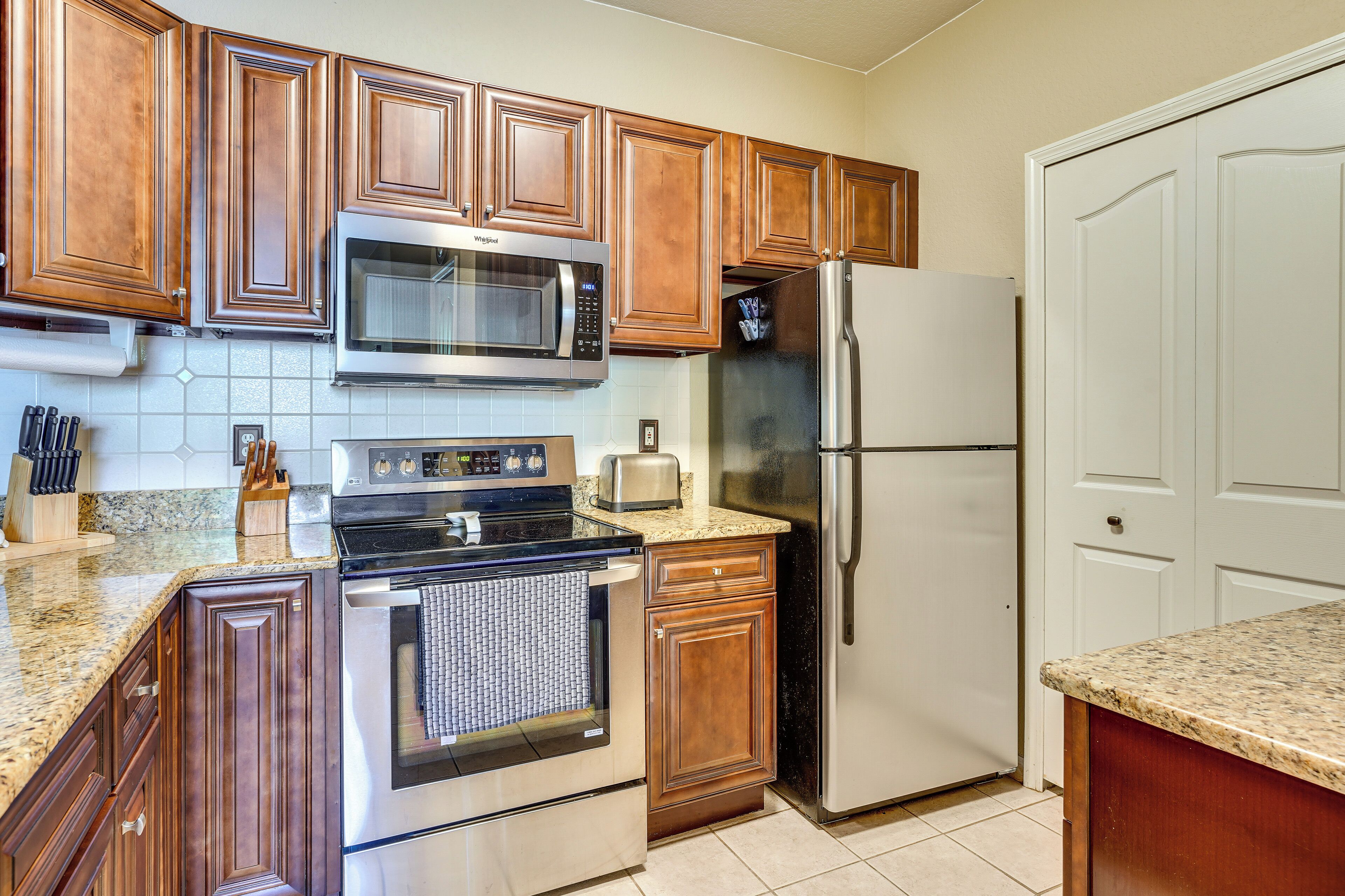 A kitchen with wooden cabinets, stainless steel appliances, and a tiled backsplash.