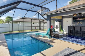 A swimming pool with a covered area, lounge chairs, and a patio with outdoor furniture. - Patio & Poolside Relaxation! Palm Coast Getaway (Palm Coast)
