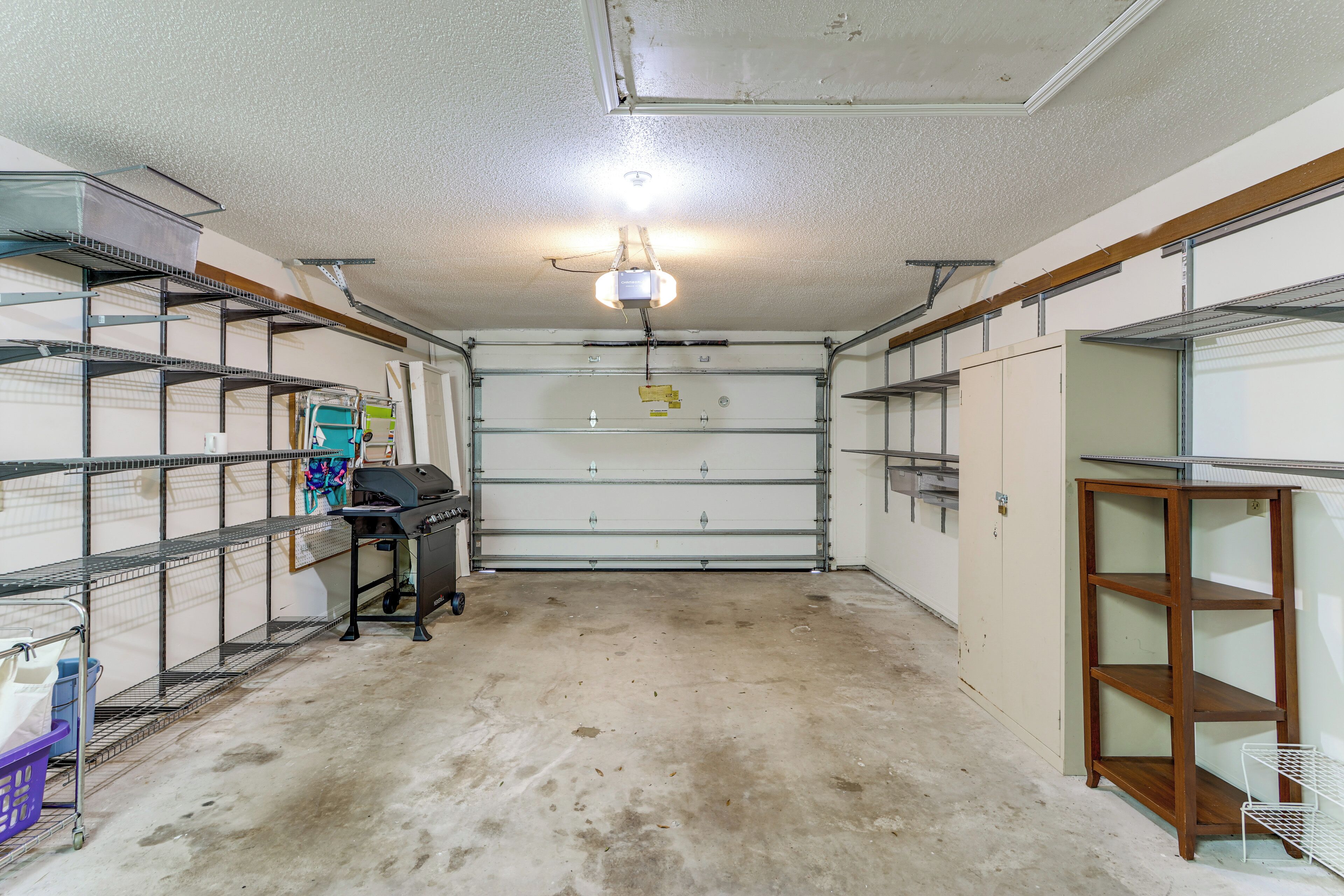 A garage with metal shelving, a ceiling fan, and a garage door.
