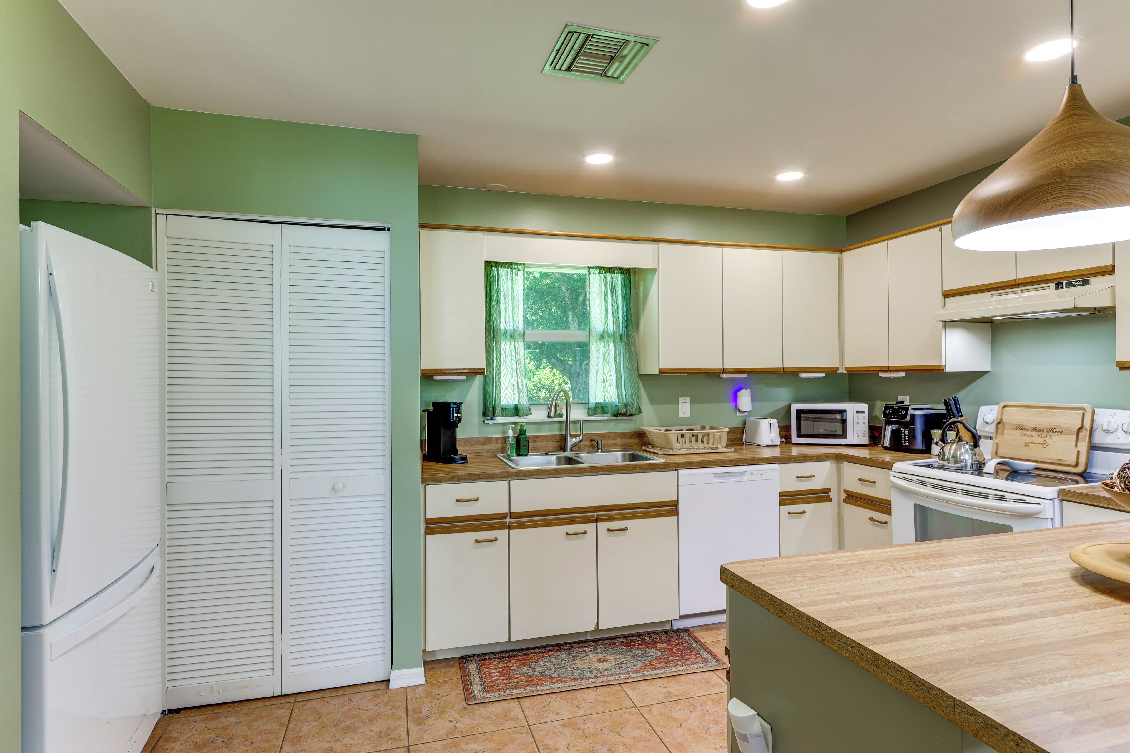 A kitchen with white cabinets, a microwave, a stove, and a sink.