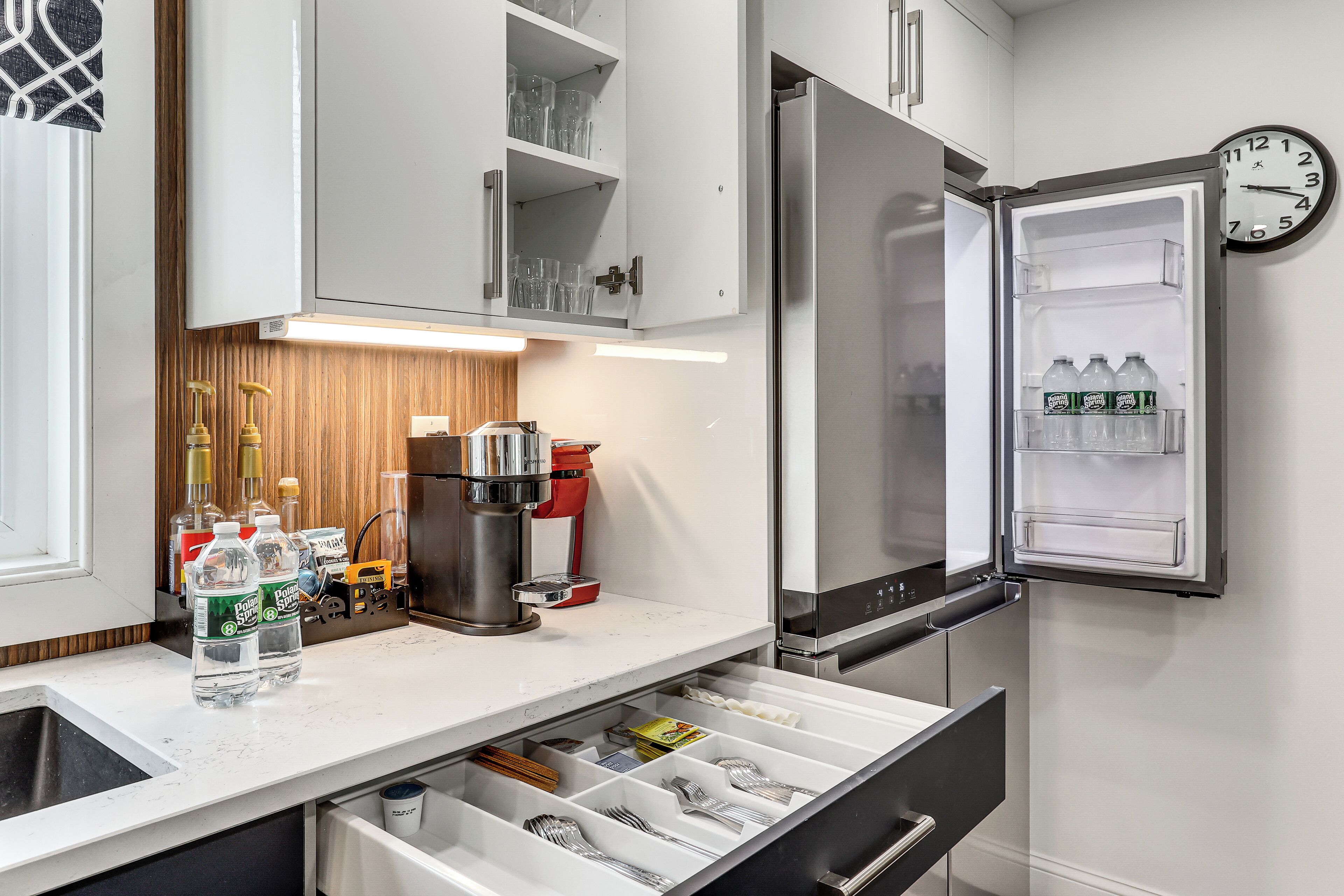 Una cocina moderna con refrigerador integrado, cafetera y organizador de cajones.