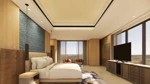 A modern hotel room with a large bed, a TV, and a view of the landscape. - Mövenpick Resort Carita (Carita)