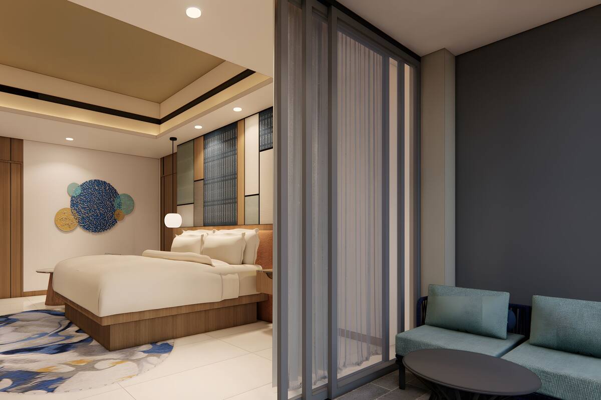 A modern bedroom with a bed, a seating area, and a large window.
