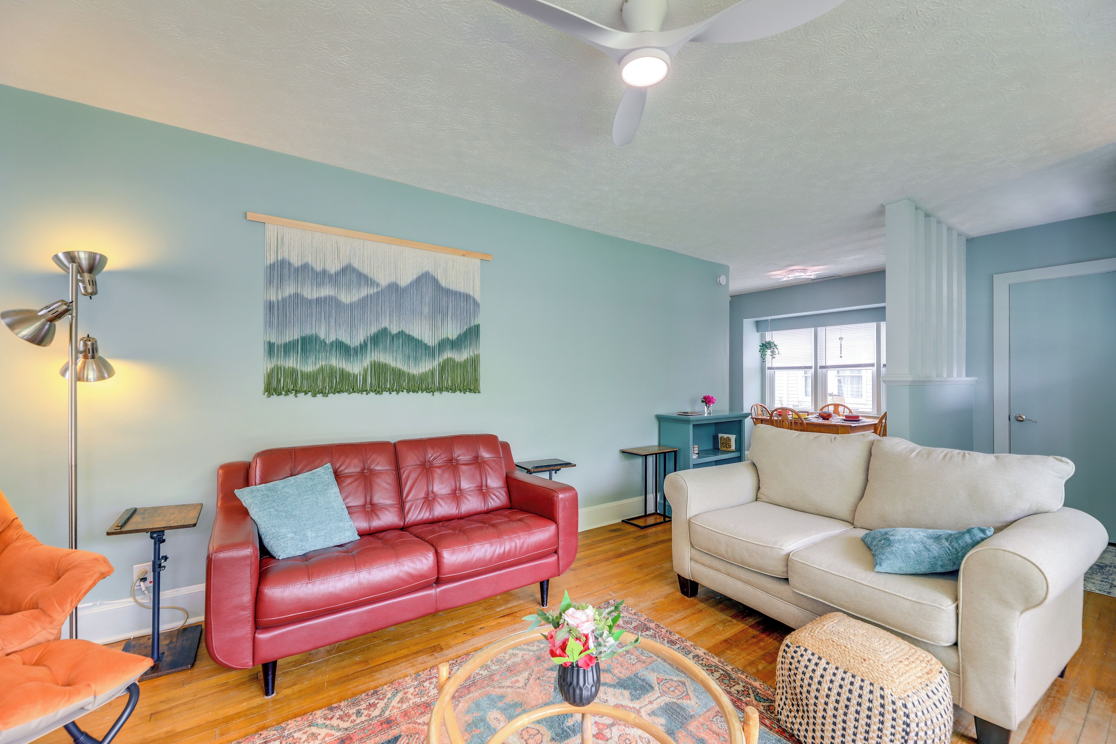 A living room with two sofas, a coffee table with flowers, a floor lamp, and a wall-mounted painting.