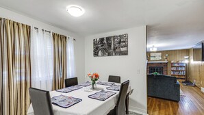 A dining area with a table set for four, a bookshelf, and a living area with a sofa and a fireplace. - Walk to Shops & Eats! Attleboro Basecamp (Attleboro)