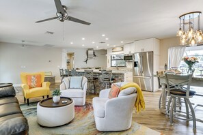Ein modernes Wohnzimmer mit Sofa, Sessel und Couchtisch, eine Küche mit Edelstahlgeräten sowie ein Essbereich mit einer Chandelier.