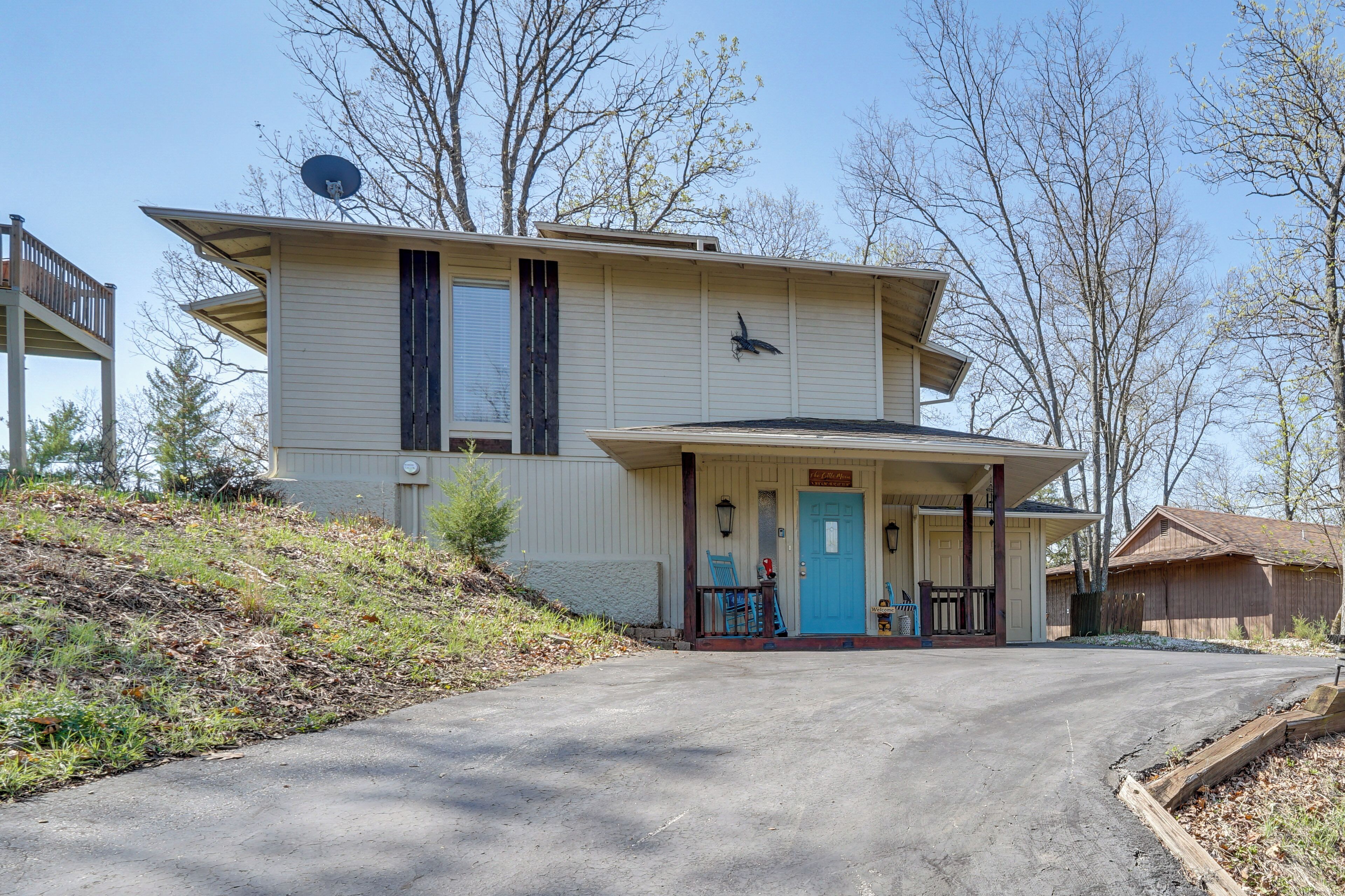 A two-story house with a front porch, a satellite dish, and a blue door.