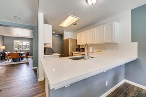 Una cocina moderna con armarios blancos, una isla grande y una zona de comedor con mesa y sillas.