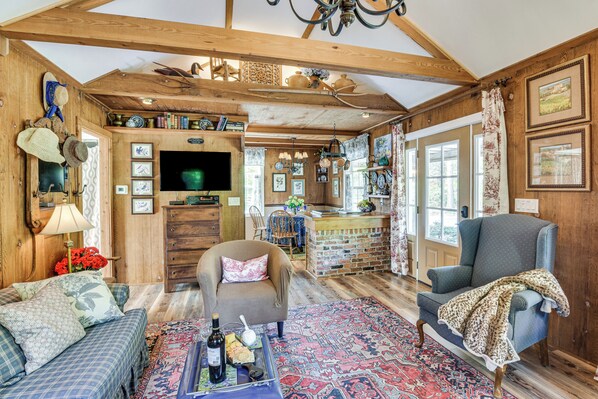 A rustic interior with wooden beams, a television, a dining area, and a patterned rug. - Quaint Couple's Cottage in Warsaw Countryside (Warsaw)