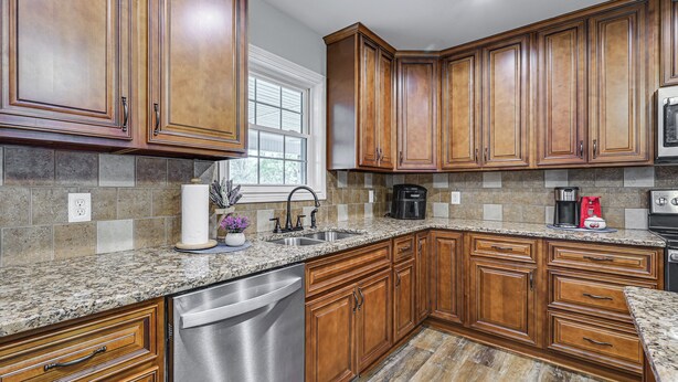 A kitchen with wooden cabinets, granite countertops, a dishwasher, and a window. - 3 Mi to Nolin Lake Boat Ramp! Family Home w/ Deck (Mammoth Cave)