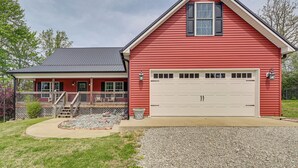 A red single-story house with a white garage, a covered porch, and a gravel driveway. - 3 Mi to Nolin Lake Boat Ramp! Family Home w/ Deck (Mammoth Cave)