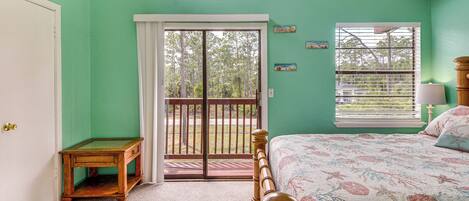 Un dormitorio con cama, una mesita, una puerta y una ventana con persianas.