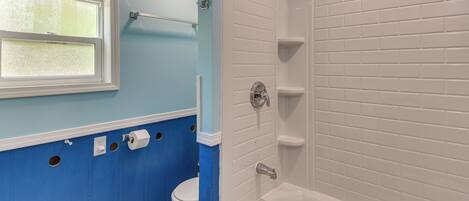 Une salle de bain avec une baignoire, des toilettes, une fenêtre et un porte-serviettes.