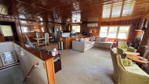 L’intérieur d’un chalet en bois comprend une cuisine, un coin repas et un salon aménagé avec un canapé et des fauteuils.