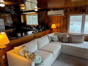 L’intérieur d’une cabane avec un canapé, une table à manger, des murs en bois et une fenêtre.