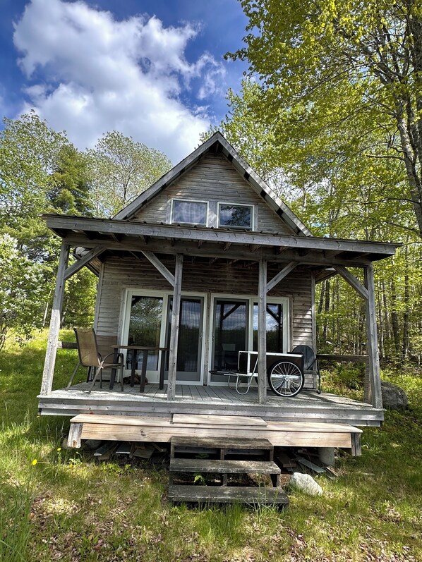 Une cabane en bois avec un porche, des portes coulissantes en verre et un vélo.