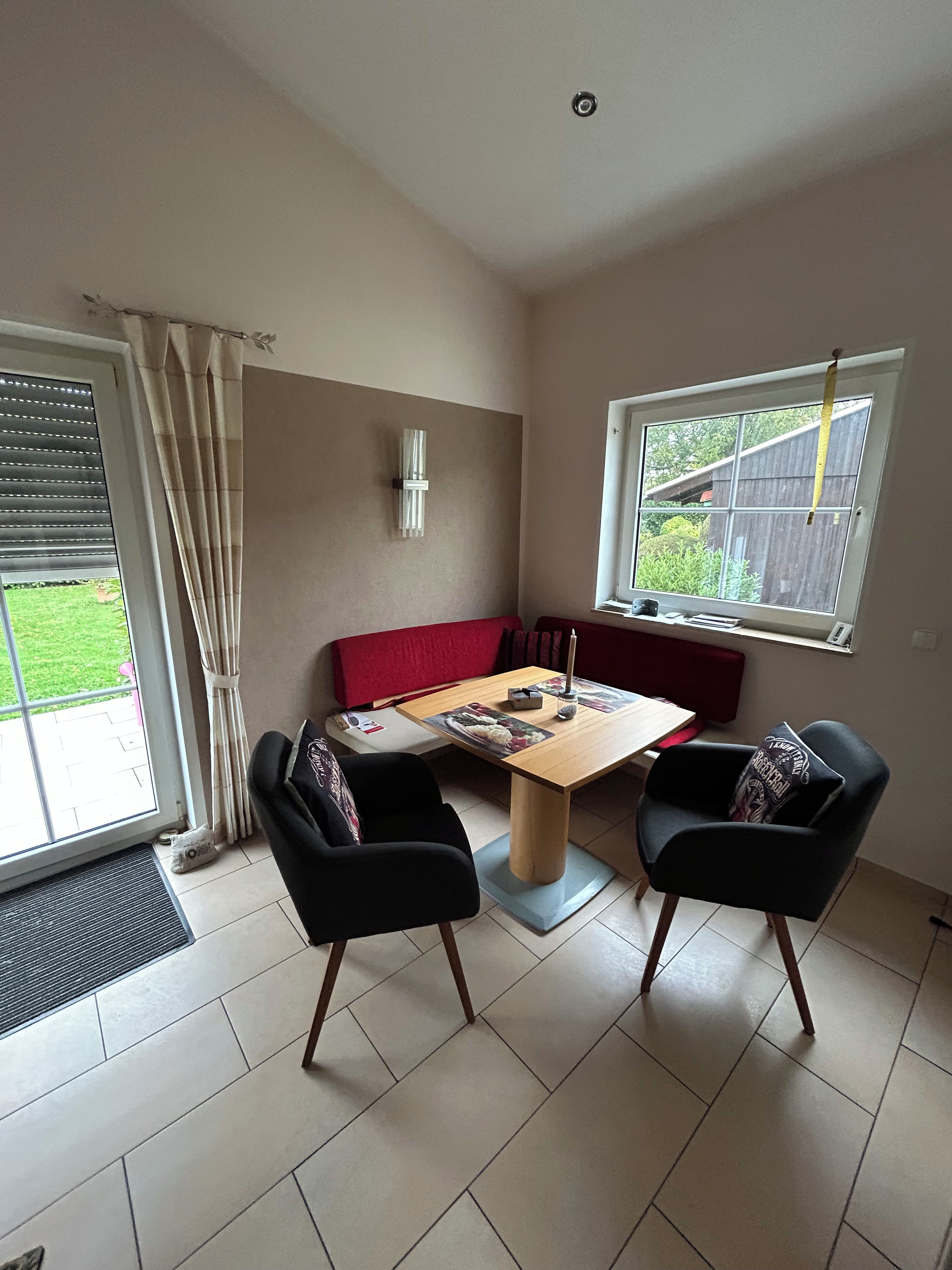 A dining area with a table, chairs, a bench, and a window with a view of greenery.